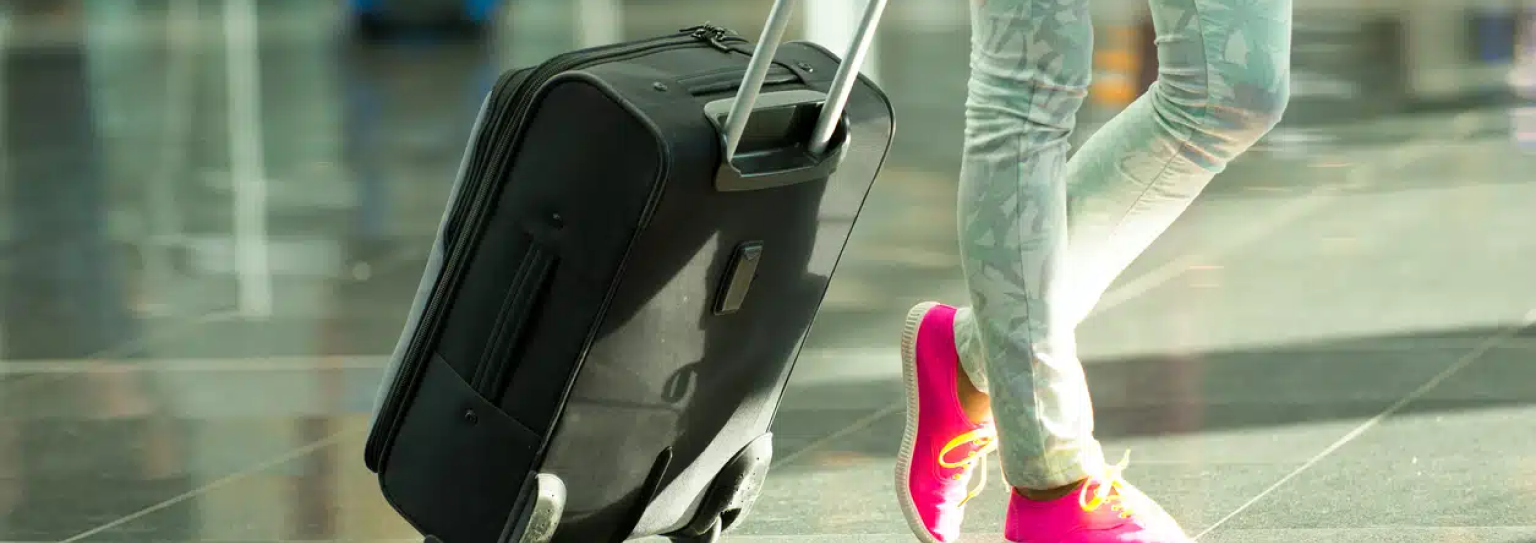 Person wheeling a suitcase through an airport.