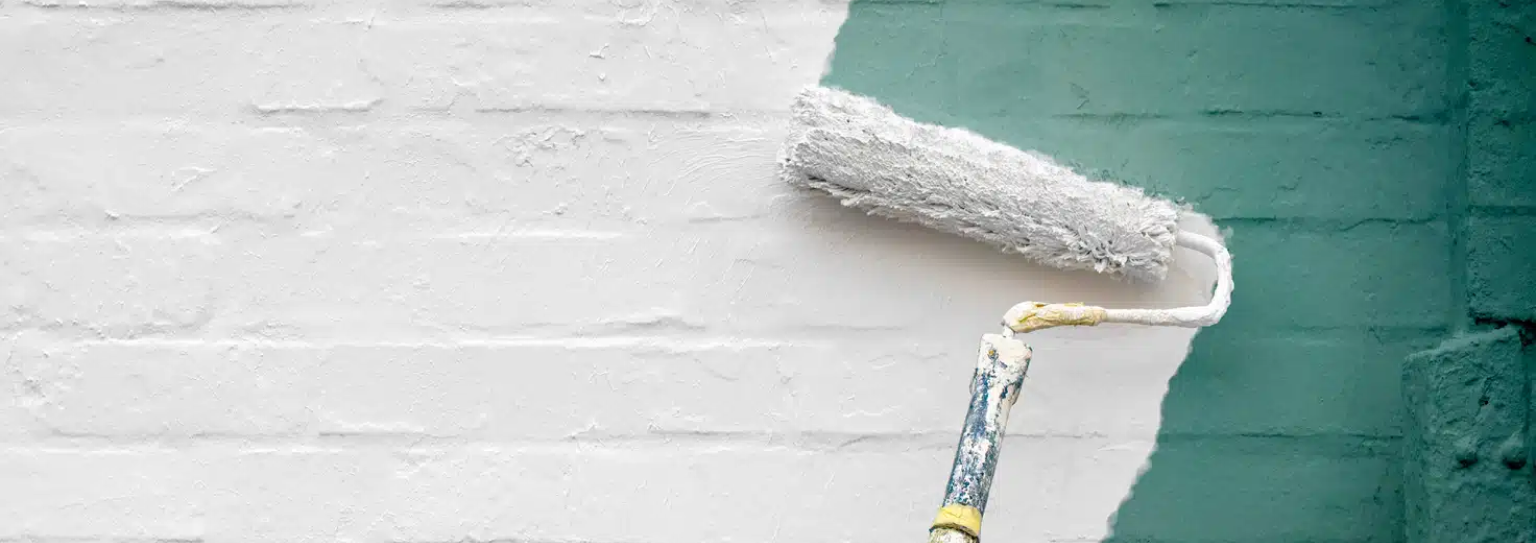 With precision and care, someone uses green paint to create a striking contrast on a previously plain white wall.